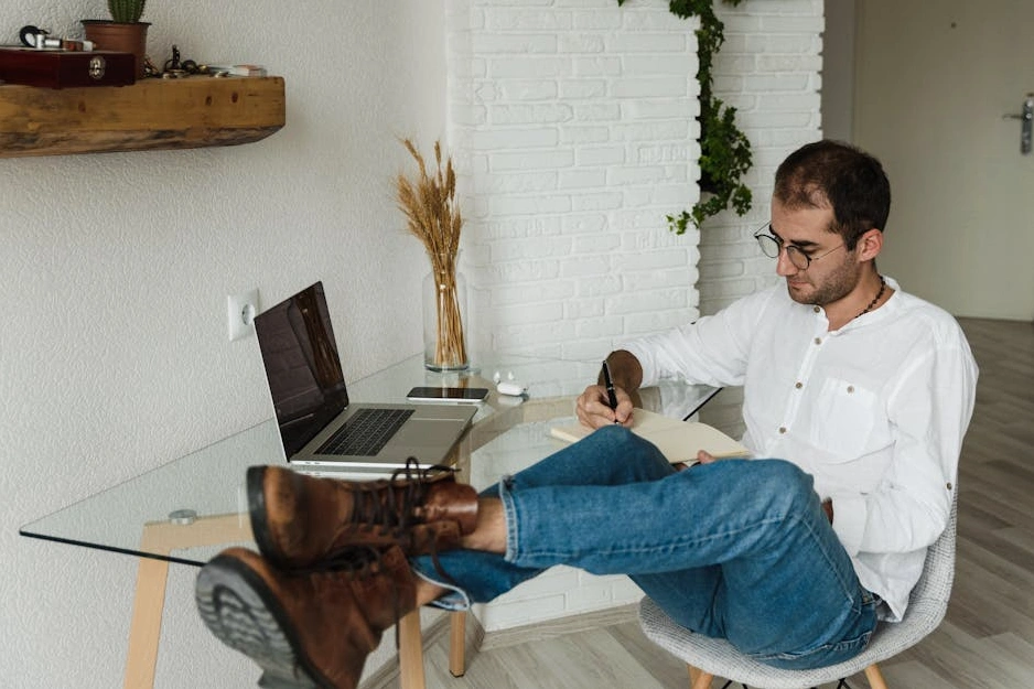 Masanın başında not defterine hedeflerini yazan bir kişi